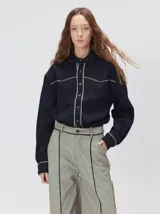 Pantalón sastrero de tiro medio y pierna ancha, con diseño a rayas verticales finas y detalle de vivos negros en la pretina y a lo largo del frente.