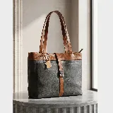 Cartera tipo tote de cuero vacuno, con diseño bicolor en gris y marrón. Cuenta con doble compartimento, cierre metálico, asas largas y una correa central decorativa con cierre de broche metálico. Incluye un detalle de etiqueta colgante de cuero.