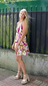 Vestido corto con estampado floral en tonos blanco, morado y dorado, con breteles finos y escote en V.