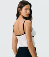 Body de encaje blanco con transparencia sutil, escote en V con ribete negro y un pequeño lazo decorativo al centro, breteles finos y diseño ajustado al cuerpo de la marca Blue Steel.