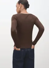 Camiseta de manga larga entallada, color marrón, con cuello en pico y detalle de ribete en color blanco.