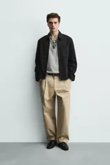 Sobrecamisa negra de corte relajado, confeccionada en tejido con mezcla de algodón elástico. Presenta cuello solapa, cierre frontal de cremallera, bolsillos de plastrón en el pecho y bolsillos de vivo en la cadera.