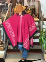 Poncho rojo de lana hilada fina, tejido en telar industrial con diseño geométrico y flecos negros en los bordes.