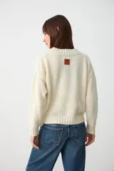 Sweater de tejido de punto color crudo, con escote en V y cuello acanalado, de diseño holgado y mangas largas.