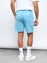 Bermuda de felpa color celeste, con cintura elástica y cordón de ajuste. Presenta el logo Umbro bordado en la pierna izquierda.