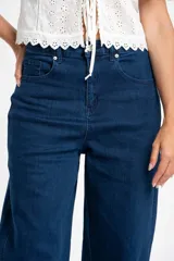 Jean de corte baggy con tiro medio, confeccionado en denim de algodón. Presenta un diseño de pierna ancha con estructura curva tipo barril y cierre frontal con botón y cremallera.
