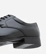 Zapato de vestir negro, confeccionado en cuero sintético, con puntera cuadrada, cierre con cordones y suela de goma.