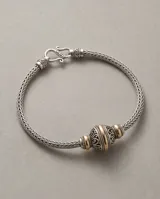Pulsera de plata 925 y lámina de oro 18k de la línea Hindi, con diseño trenzado y una esfera central decorada con detalles tallados.
