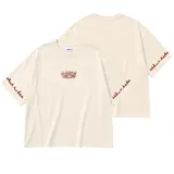 Remera oversize color beige, con cuello redondo y mangas cortas. Presenta un pequeño estampado frontal con la inscripción "Lrola Since 2020" y detalles de llamas marrones en los dobladillos de las mangas.
