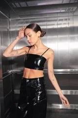 Top corto negro de charol con escote recto y espalda con cierre desmontable central.