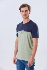 Remera de algodón y poliéster de corte clásico, con diseño en bloques de color negro en la parte superior y gris melange en la inferior. Presenta cuello redondo, mangas cortas y un pequeño estampado tipográfico en el pecho.
