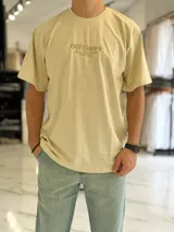 Remera oversize color beige con diseño bordado en el pecho con las palabras Off Court Game Set Match Duxon Team.
