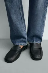 Mocasín de piel negra para hombre, con detalle de antifaz en el empeine, costuras visibles, horma cuadrada y suela ultrafina.