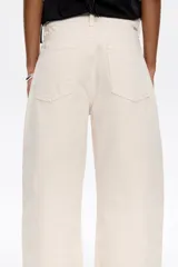 Pantalón vaquero de algodón orgánico color blanco crudo, tiro medio, corte barrel ancho y largo tobillero. Presenta bolsillos redondeados delanteros y bolsillos plastrón traseros.