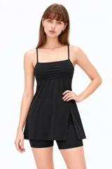 Vestido corto negro de poliamida, con tirantes finos regulables tipo lencero, escote recto y diseño ajustado con falda evasé con tajo lateral.