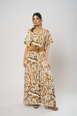 Vestido largo de corte fluido con estampado abstracto en tonos tierra, ocre y blanco. Presenta mangas tipo murciélago, escote en V profundo y un tajo frontal. Incluye un sistema de ajuste regulable en la cintura.