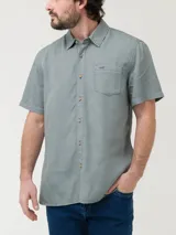 Camisa de manga corta RKF confeccionada en tencel, color verde grisáceo. Presenta cuello clásico, cierre frontal con botones claros, bolsillo en el pecho con bordado del logo del pato al tono y pinza en la espalda.