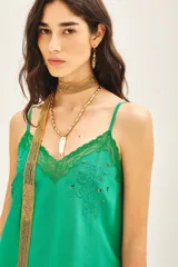 Top de crepe viscosa color verde azulado, con escote en V adornado con encaje y bordados florales con lentejuelas. Posee breteles finos regulables y elástico en la espalda.