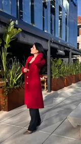 Tapado rojo con cuello solapa, cierre frontal con botones dorados y corte a la rodilla.
