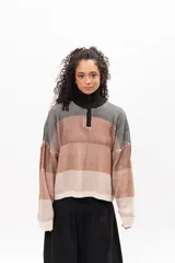 Buzo de tejido de punto con diseño a rayas horizontales en tonos tierra, negro y crema. Presenta cuello alto con cierre frontal parcial, mangas largas con puños ajustados y corte holgado.