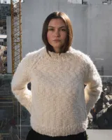 Sweater de cuello redondo tejido a mano en dos agujas, confeccionado en una mezcla de lana merino y seda. Presenta un diseño de punto grueso con detalle de bordado artesanal en color azul.
