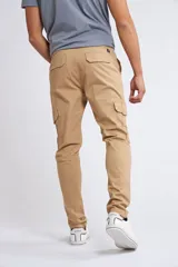 Pantalón cargo de corte slim, color beige, con cierre y botón frontal, bolsillos laterales tipo cargo y terminación recta sin puños.