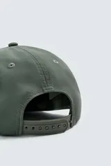 Gorra de cinco paneles color verde oliva con visera plana y ajuste trasero. Presenta un bordado frontal en negro con la frase "Time in art, music and coffee. Notting Hill, London".