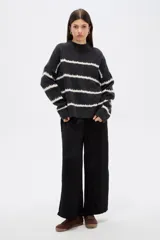 Sweater de punto con diseño de rayas horizontales en contraste, cuello alto y corte holgado con mangas largas.