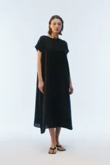 Vestido largo negro de lino, con corte evasé, escote redondo, mangas cortas, bolsillos laterales y ruedo asimétrico.