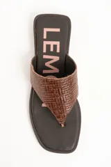 Sandalias de cuero color marrón, tipo ojota con taco bajo, tira ancha con textura trenzada y plantilla con inscripción de la marca.