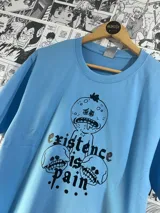 Remera celeste con estampa gráfica de Mr. Meeseeks y calaveras con la frase "Existence is pain".