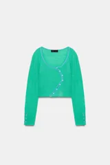 Chaqueta corta de punto color verde menta, con escote cuadrado y ribete azul celeste a contraste. Manga larga con botones decorativos en los puños y cierre frontal asimétrico con botones.