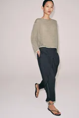 Sweater de punto fino color beige con finas rayas horizontales negras, cuello redondo y manga larga.