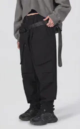 Pantalón de estilo utilitario oversize confeccionado en tejido técnico ripstop. Presenta cintura elástica con broche tipo mochilero, bolsillos cargo frontales de gran tamaño con cierre, bolsillos traseros tipo ojal y sistema de ajuste en los tobillos mediante broches a presión.
