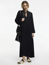 Vestido largo tipo túnica de corte holgado, con mangas largas amplias, cuello con lazo ajustable y tajos laterales en el ruedo. Incluye bolsillos ocultos.