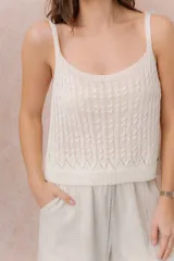 Top de punto color crudo, con tirantes finos, escote redondo y diseño calado con textura.