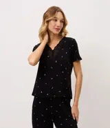 Pijama largo negro de viscolycra con estampa floral, compuesto por una remera de manga corta con escote en V y aplicación de encaje, y un pantalón con cintura elastizada.