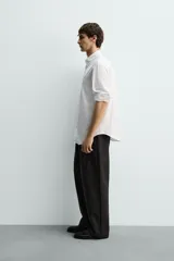 Camisa de corte regular fit confeccionada en tejido de algodón con textura. Presenta cuello abotonado, manga larga con puños abotonados y cierre frontal con botones.