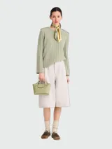 Cartera tipo tote en tamaño extra pequeño, confeccionada en cuero de color verde oliva. Presenta una estructura rígida con asas cortas redondeadas y un cierre de solapa con broche metálico dorado grabado con el logo de la marca.