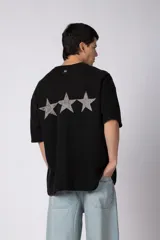 Remeron de corte oversize color negro, con estampa frontal en color gris desgastado que incluye el texto 'CNPT' y tres estrellas. Presenta cuello redondo y mangas cortas amplias.