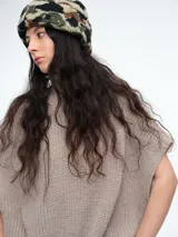 Chaleco tipo poncho de tejido de punto color tostado, con cuello polera y diseño holgado con laterales abiertos.