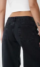 Pantalón de jean estilo wide leg, de tiro bajo y corte holgado, en color negro lavado.