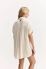 Vestido camisero corto color coral, de silueta amplia y suelta, con manga corta, cuello clásico y cierre frontal de botones.