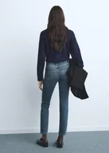Jeans slim tiro alto de color azul, con diseño crop, cierre de botón y cremallera, trabillas y cinco bolsillos.