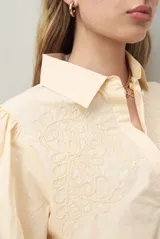 Camisa blanca de mangas 3/4 abullonadas con bordado floral en el frente.