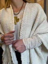 Ruana color crema tejida en telar liso con flecos.