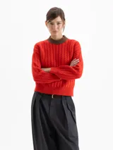 Sweater de punto con diseño de ochos y rayas verticales en color rojo. Presenta cuello redondo, puños y cintura en contraste de color marrón oscuro.