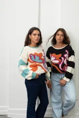 Buzo de punto con diseño de flores abstractas en colores vibrantes y mangas a rayas. Presenta cuello redondo y puños tejidos.