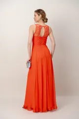 Vestido largo color coral con escote halter, corsé superior bordado con piedras y falda amplia y ligera de gasa.