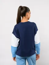 Buzo de cuello redondo con diseño de bloques de color en rojo, blanco y azul. Presenta el logo de Umbro y el escudo del Club Nacional de Football bordados en el pecho.